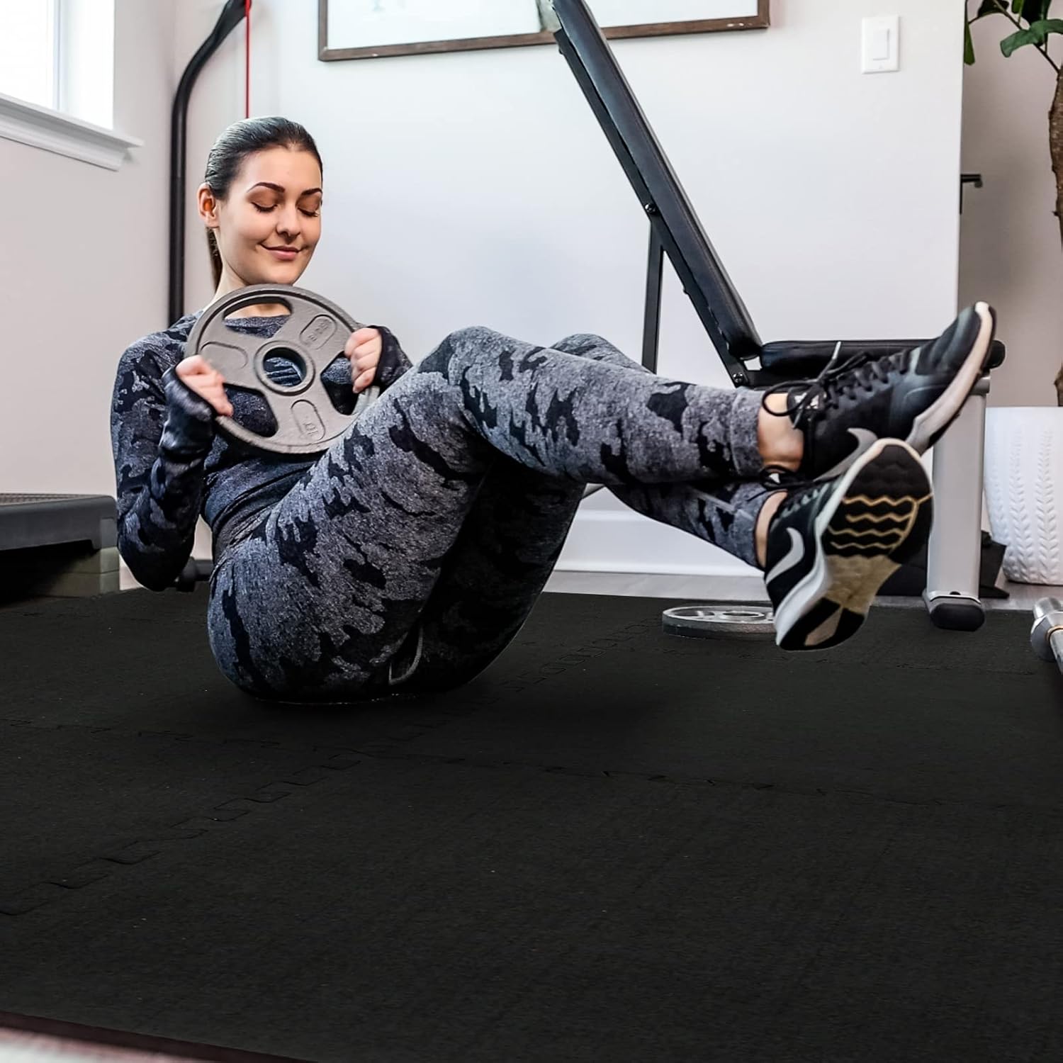 Woman exercising on Alephneta GroundGuard™ mat in a home gym setting.